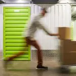 Fast Delivery to Storage Unit Blurred motion shot of unrecognizable man pushing cart with boxes while running in self storage facility, copy space